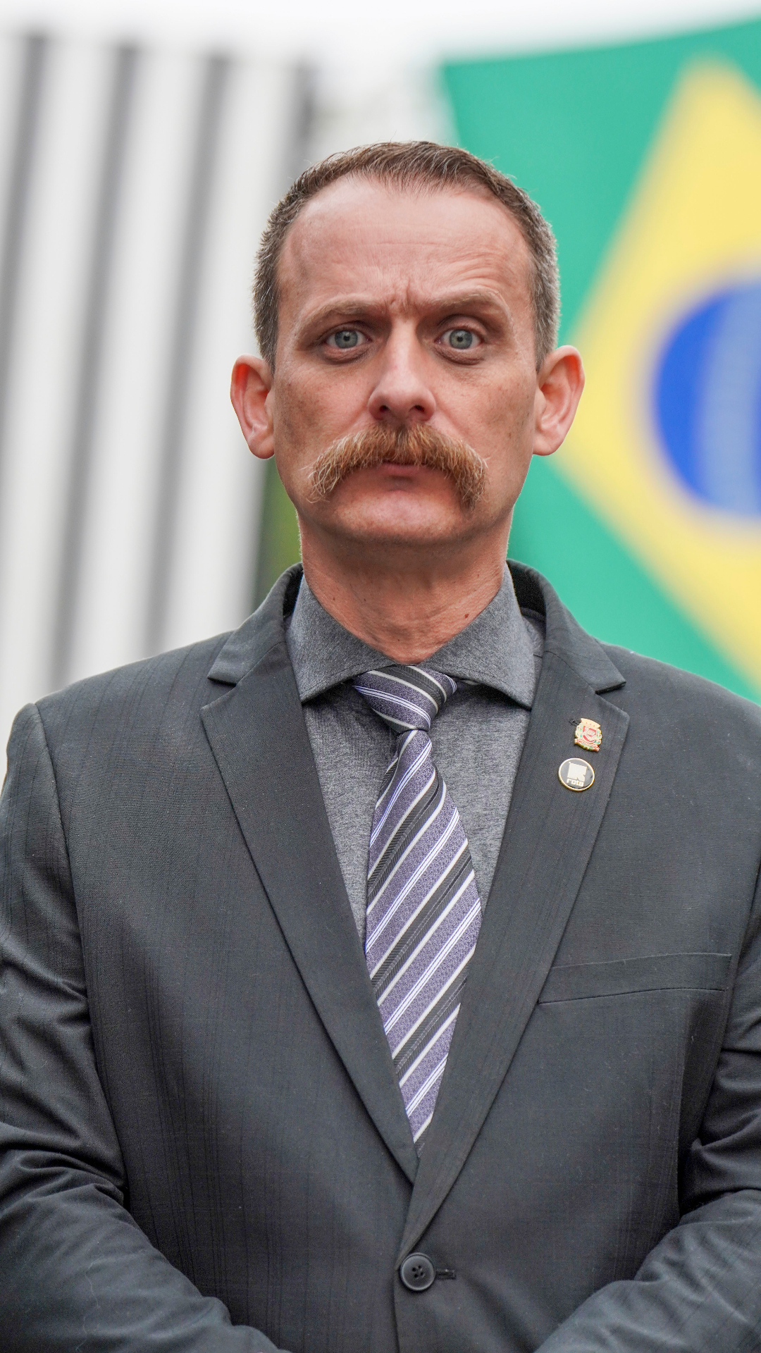 Sargento Nantes em solenidade institucional com bandeira do Brasil